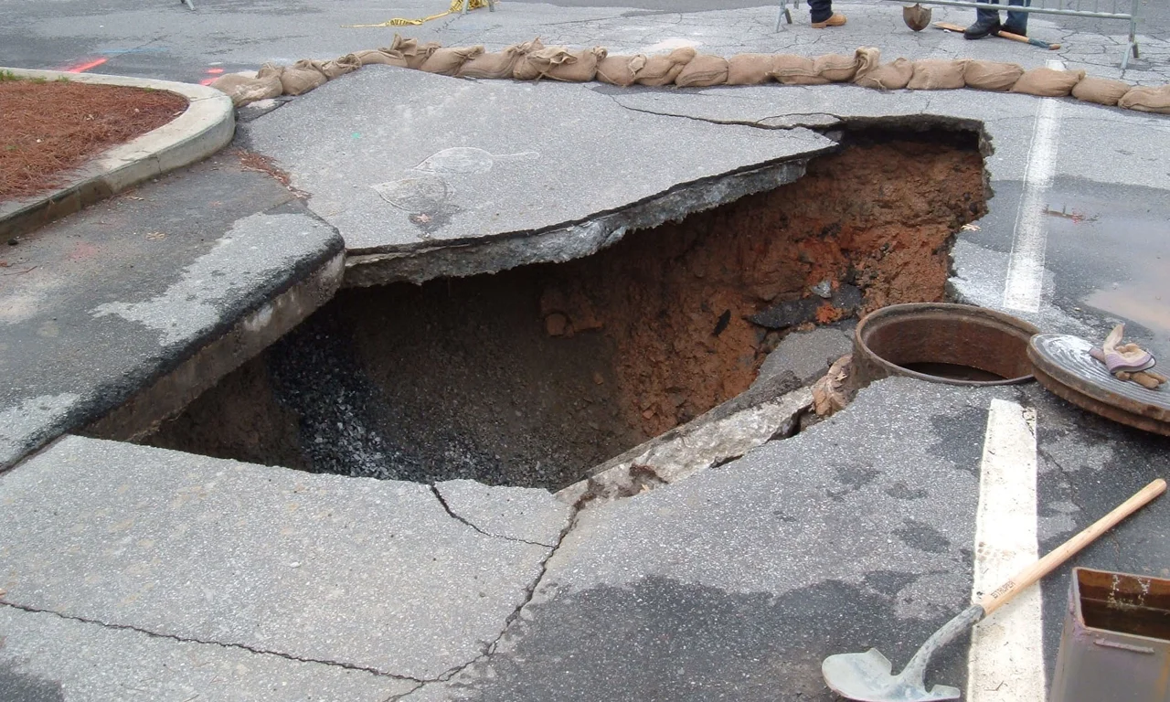 This is a sinkhole in a parking lot at Georgia Tech in Atlanta, GA, USA.
A contractor I spoke with said the hole was 32 feet deep. It was formed as rainwater leaked through the pavement and into a break in the sewer line below.